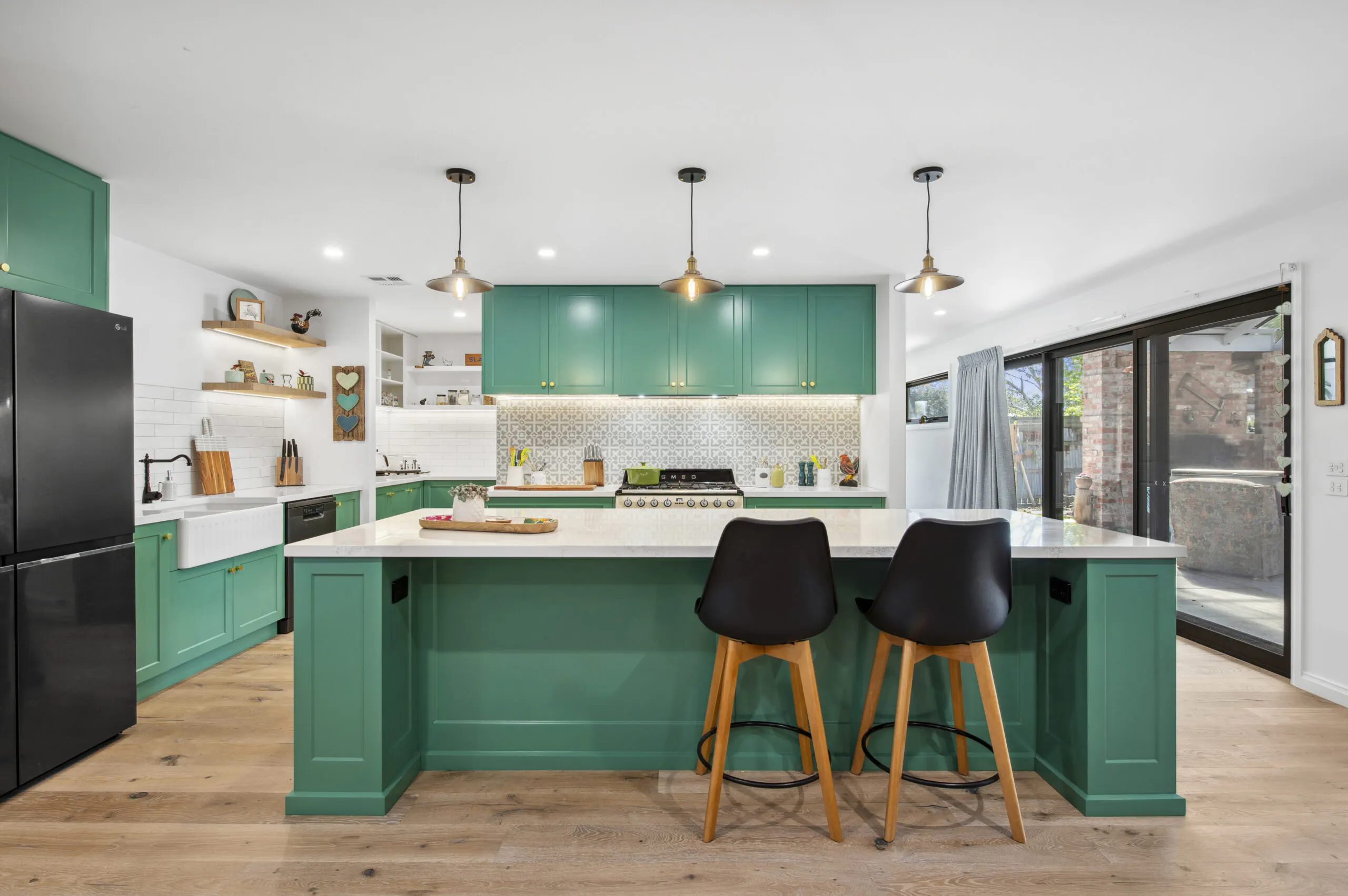Green shaker kitchen with an island bench and black stools