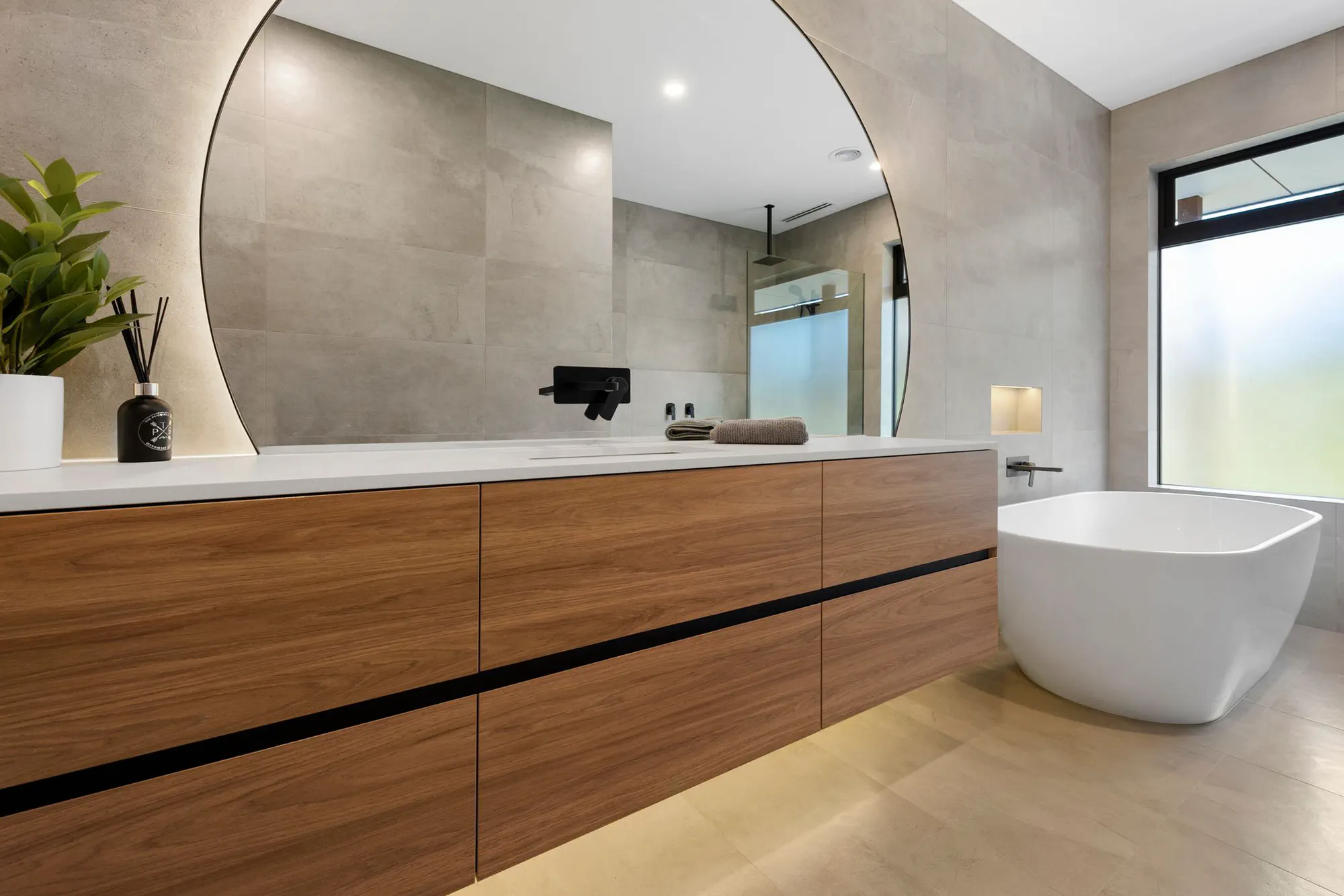 Timber floating vanity with a round mirror and freestanding bath
