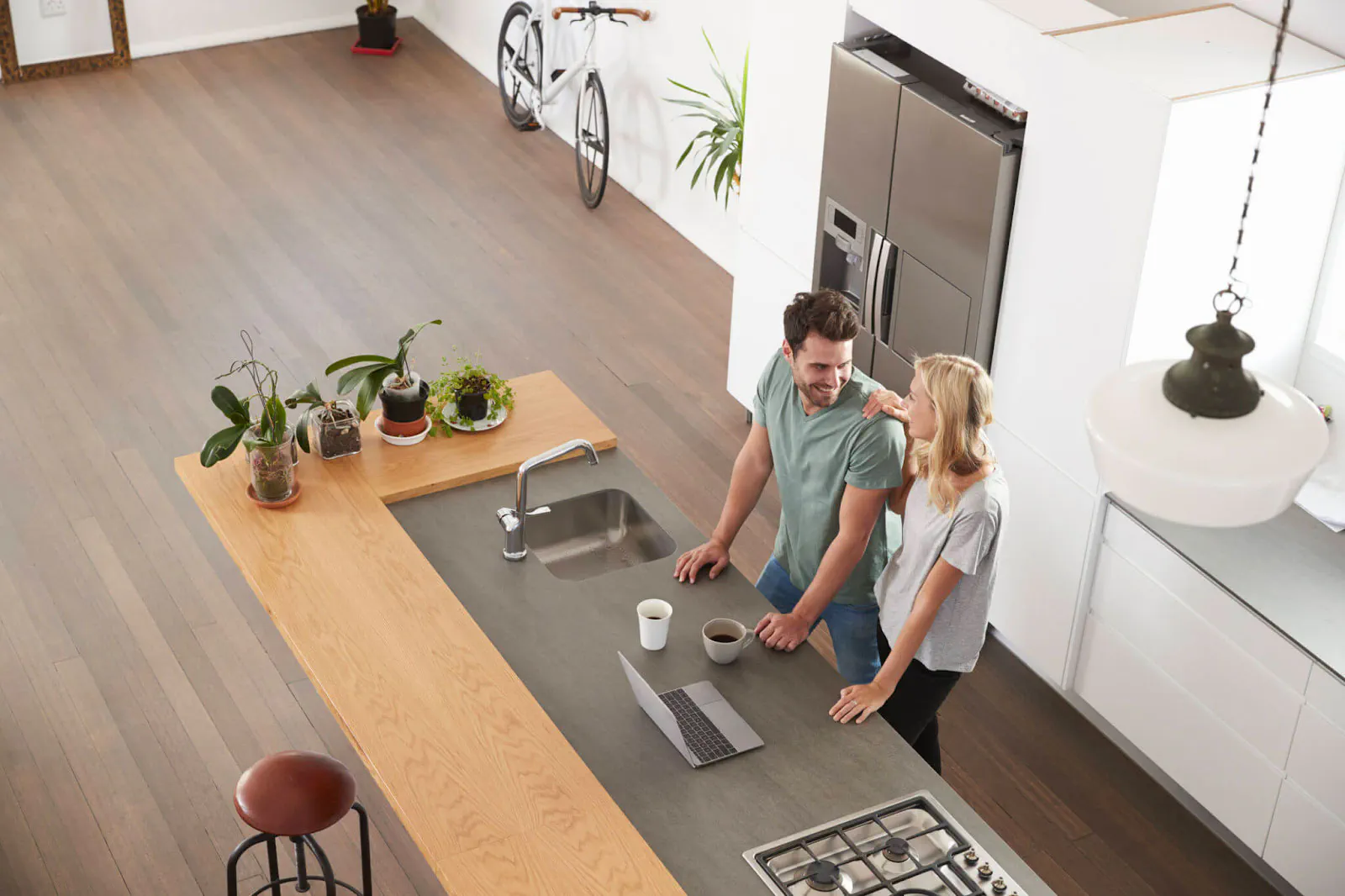 Timber-topped kitchen island with a couple preparing food