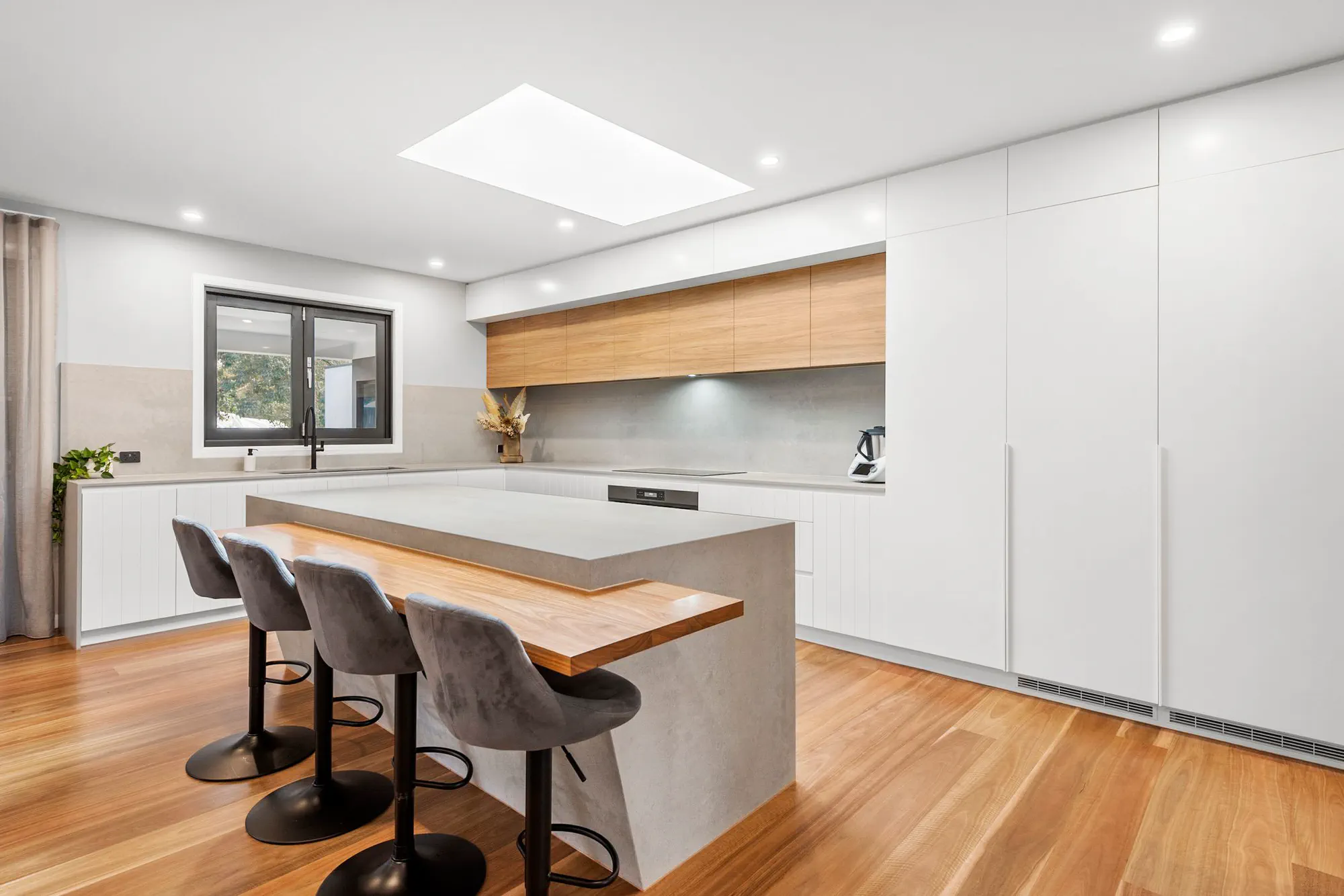 White kitchen with timber shelving and an island bench