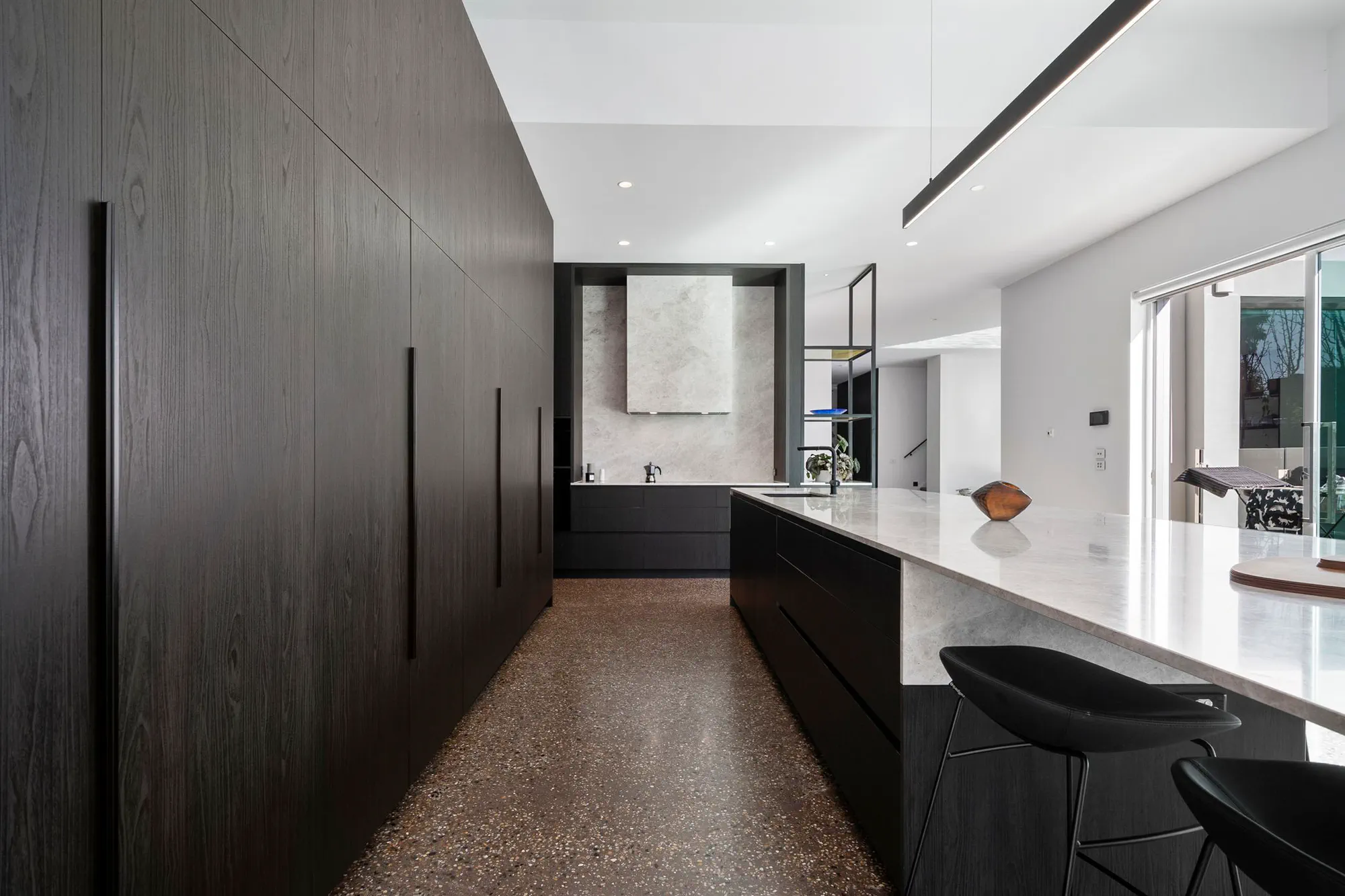 Floor-to-ceiling dark cabinetry beside a stone island