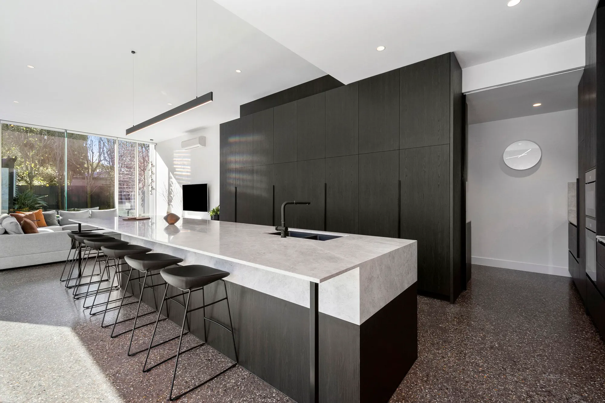 Open-plan kitchen with dark timber cabinetry and a stone island