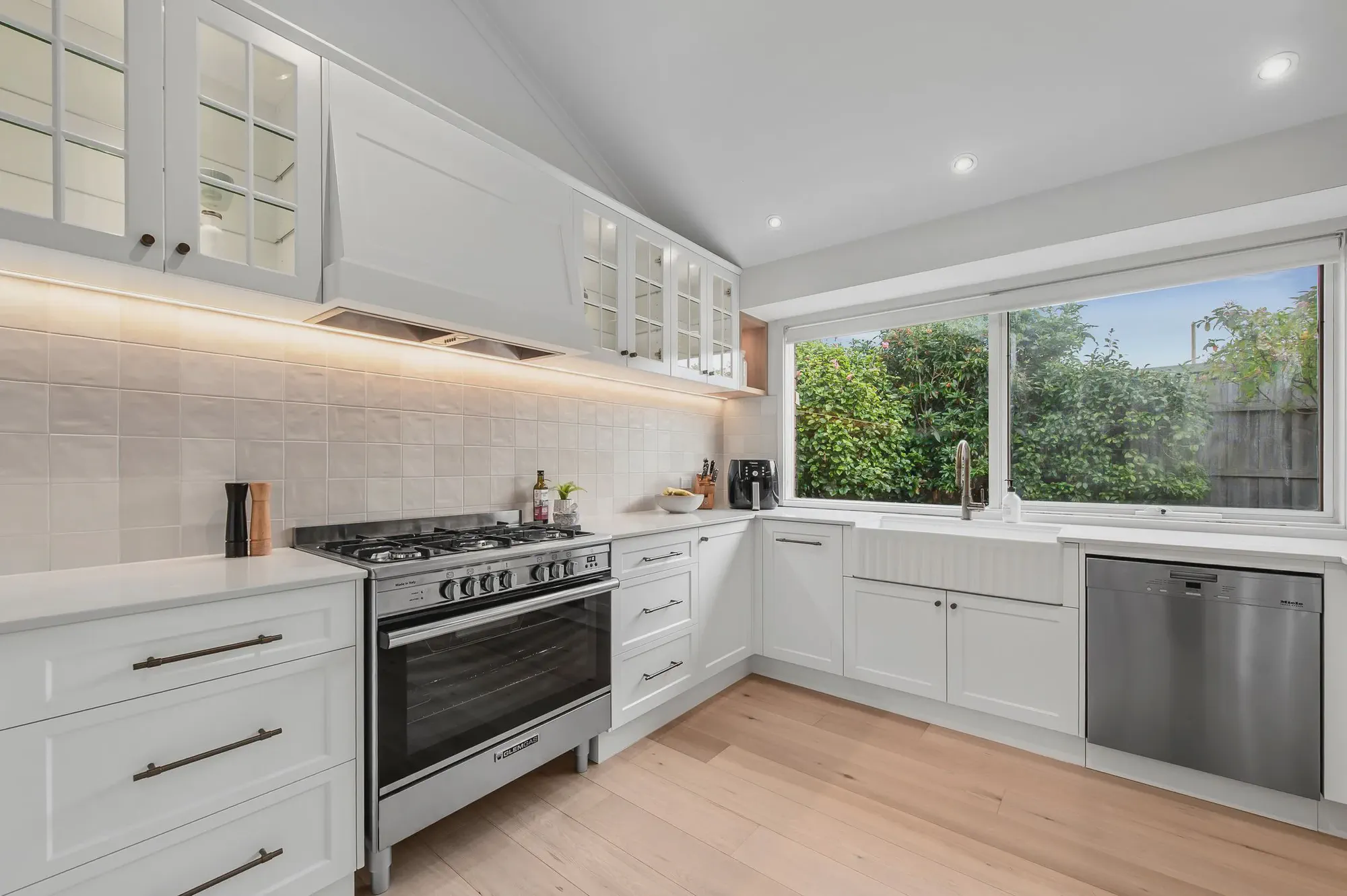 White shaker kitchen with a gas cooktop and open timber shelving